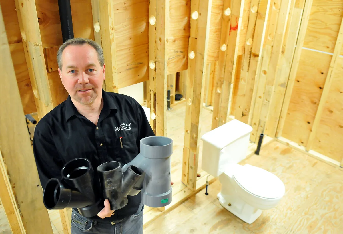 A plumber working under a sink with professional tools